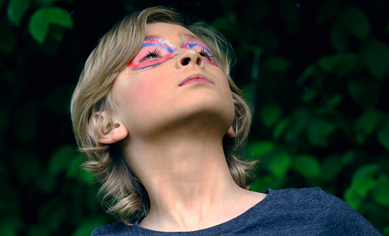 child looking up with colourful face paint