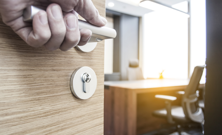 the hand of a man in a suit opening an office door