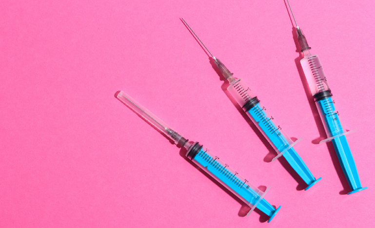 crossed syringes on a pink background