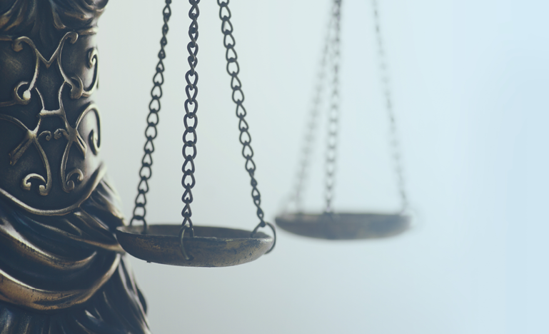 A close-up of a decorative balance scale with ornate details, highlighting one side of the scale in soft lighting.