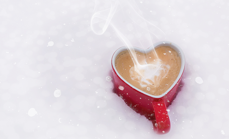 A red, heart-shaped mug sits in the snow